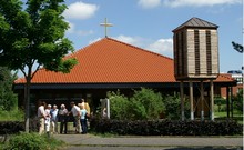DIe Gemeinde vor der Holzkirche mit dem alten Glockenturm